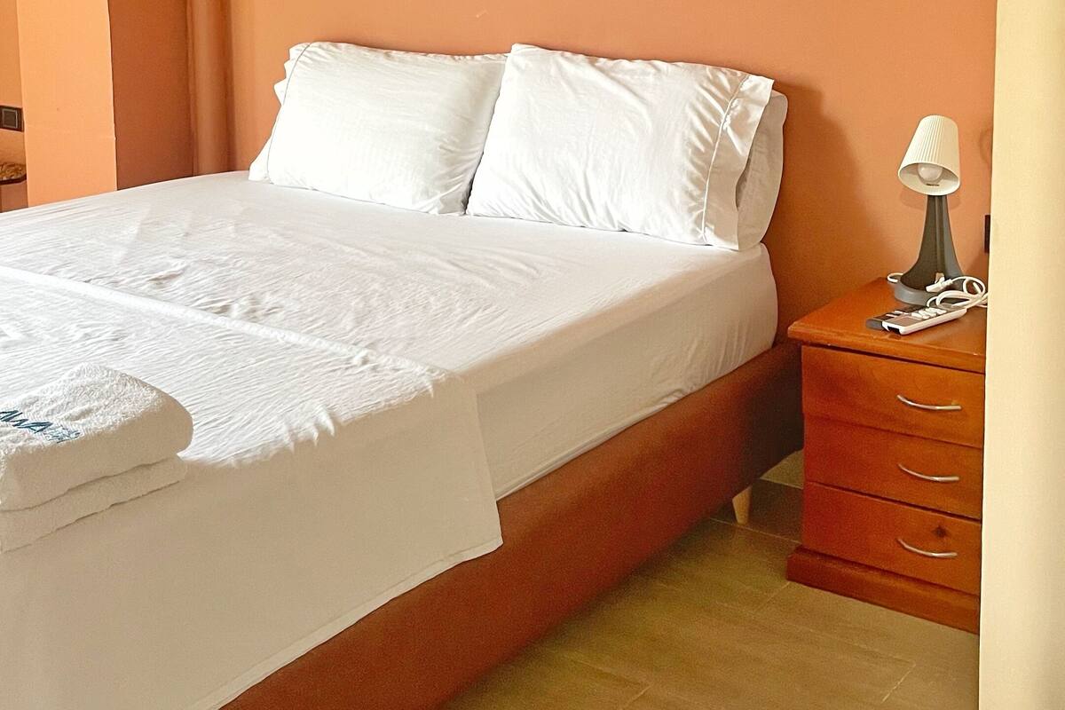Ein Schlafzimmer mit einem Bett, einem Nachttisch und drei gerahmten Bildern an der Wand.
