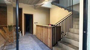 Ein Korridor mit einem Holzboden, einer Treppe und einer Glastür zu einem weiteren Raum.
