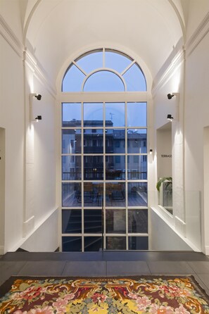 A grand entrance with a large arched window, a staircase, and a patterned rug. - Best Western Grand Hotel de Castres (Castres)