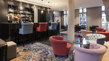 Una zona de bar con varios taburetes, una alfombra estampada y una mezcla de sillones y sofás.