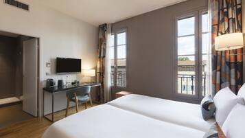 Une chambre d’hôtel équipée d’un lit, d’un bureau, d’une chaise, d’une télévision et d’une fenêtre avec des rideaux.