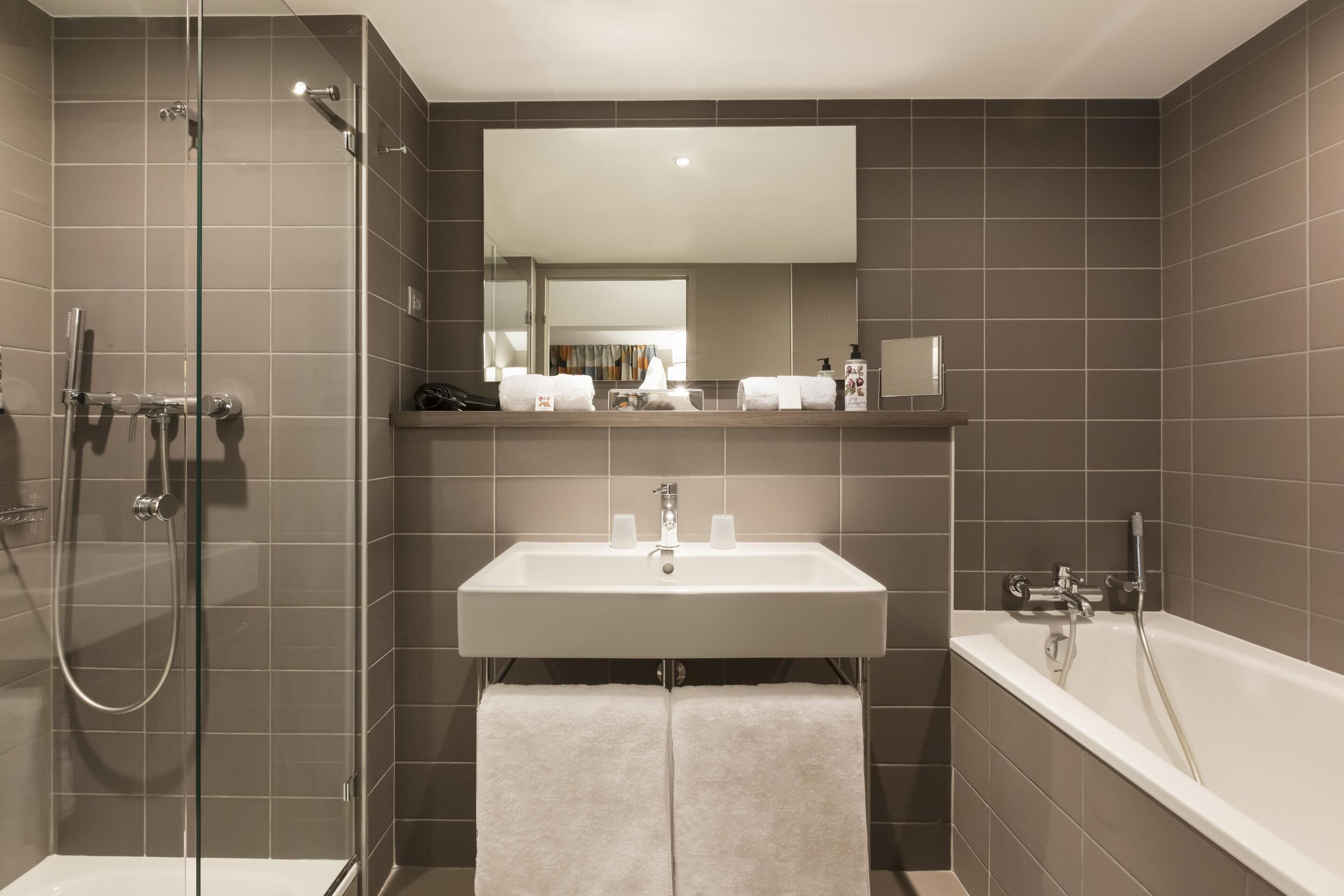 Une salle de bain équipée d’une douche, d’un lavabo et d’une baignoire, le tout doté d’accessoires modernes.