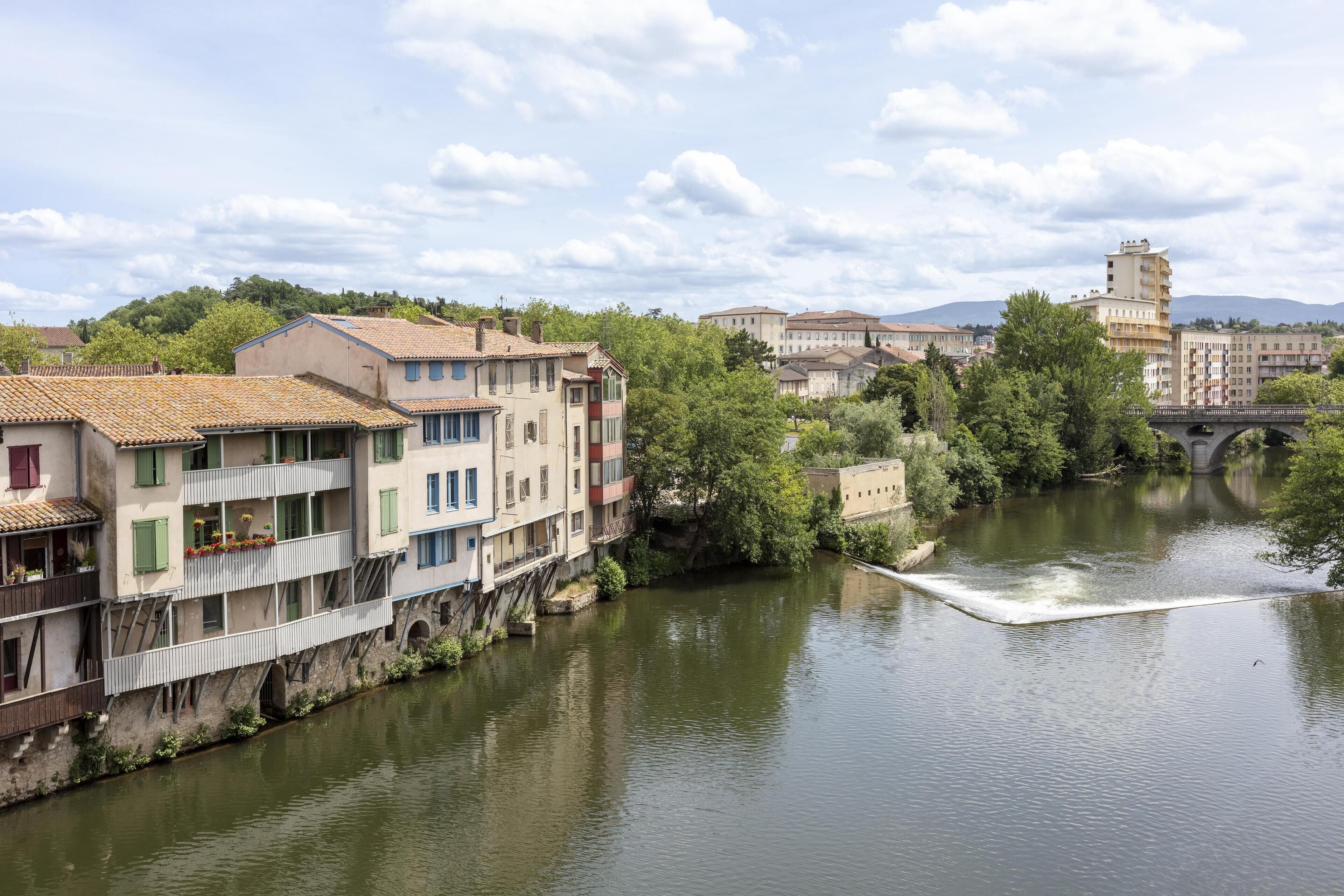 Un río con edificios a un lado y un puente a lo lejos.