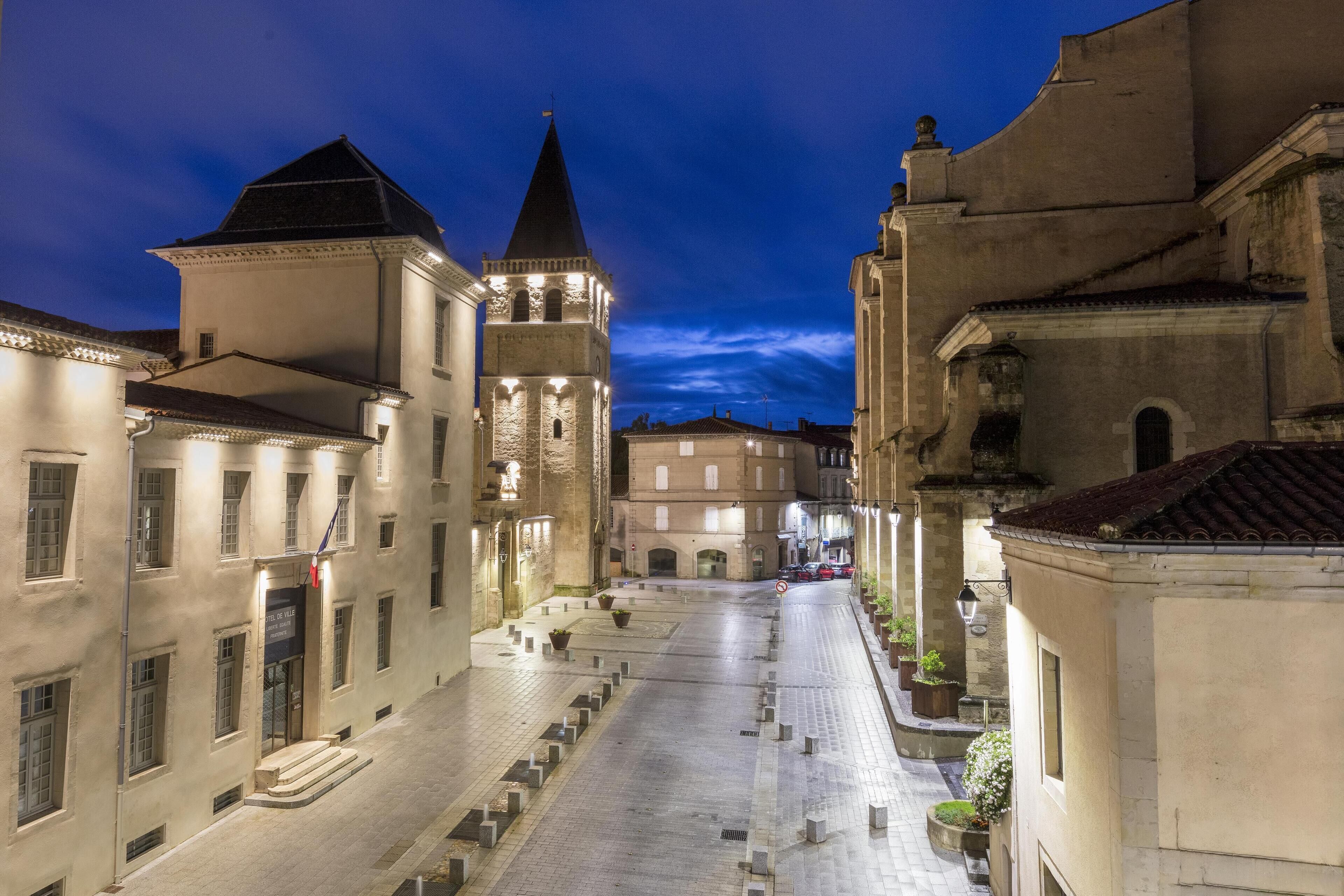 Una calle histórica con edificios, una torre y un cielo despejado.