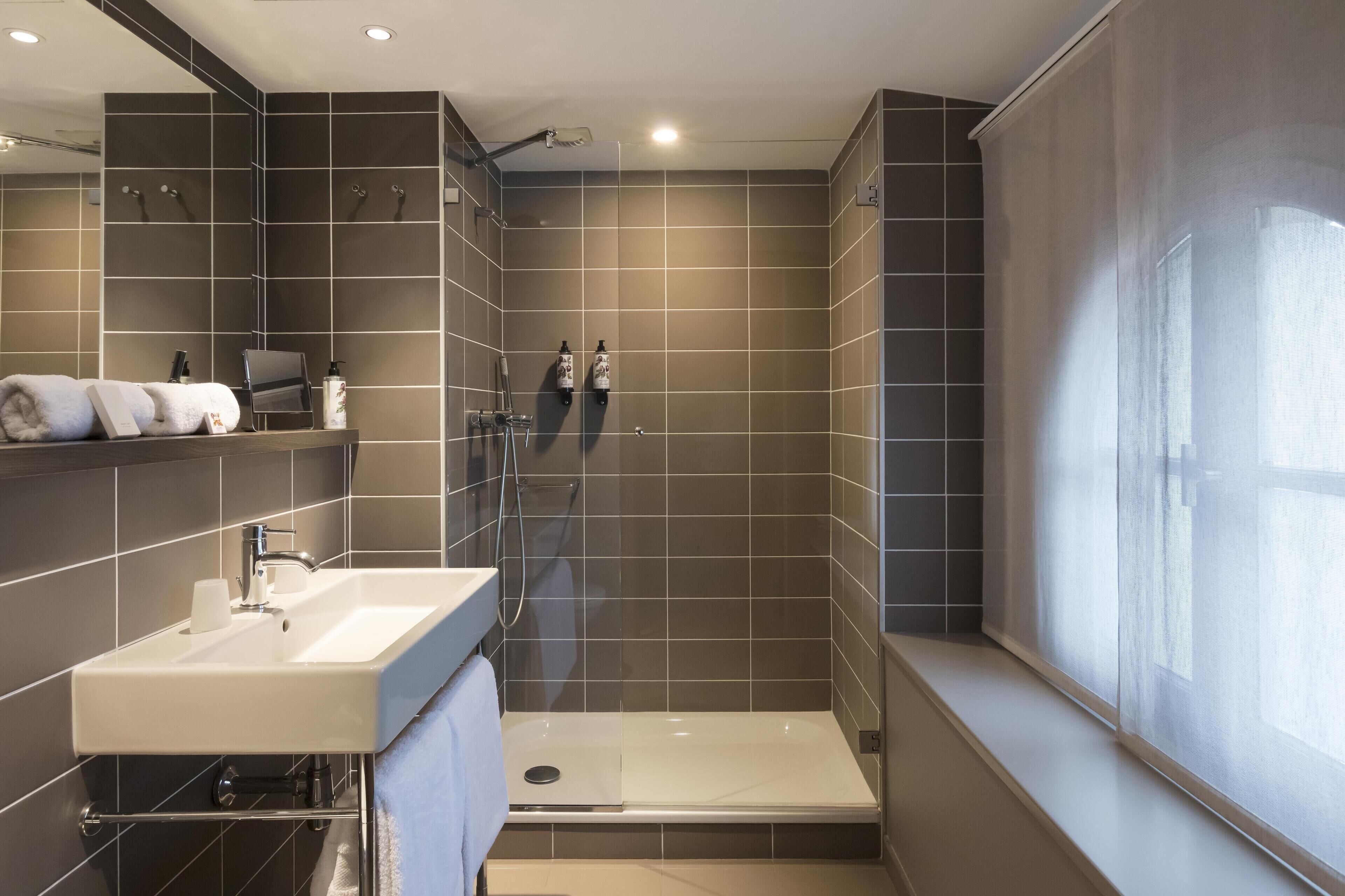Ein modernes Badezimmer mit Dusche, Waschbecken und einem großen Spiegel.