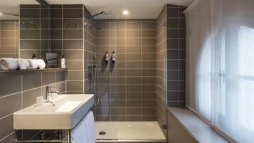 Ein modernes Badezimmer mit Dusche, Waschbecken und einem großen Spiegel.