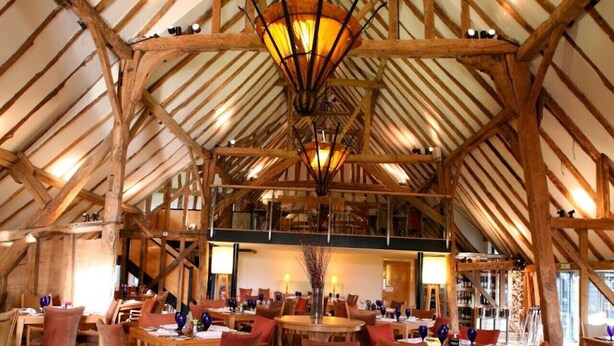 A spacious hall with high wooden beams and a central chandelier, furnished with tables and chairs. - Cozy Cottage With Scenic Walks (Great Tey)