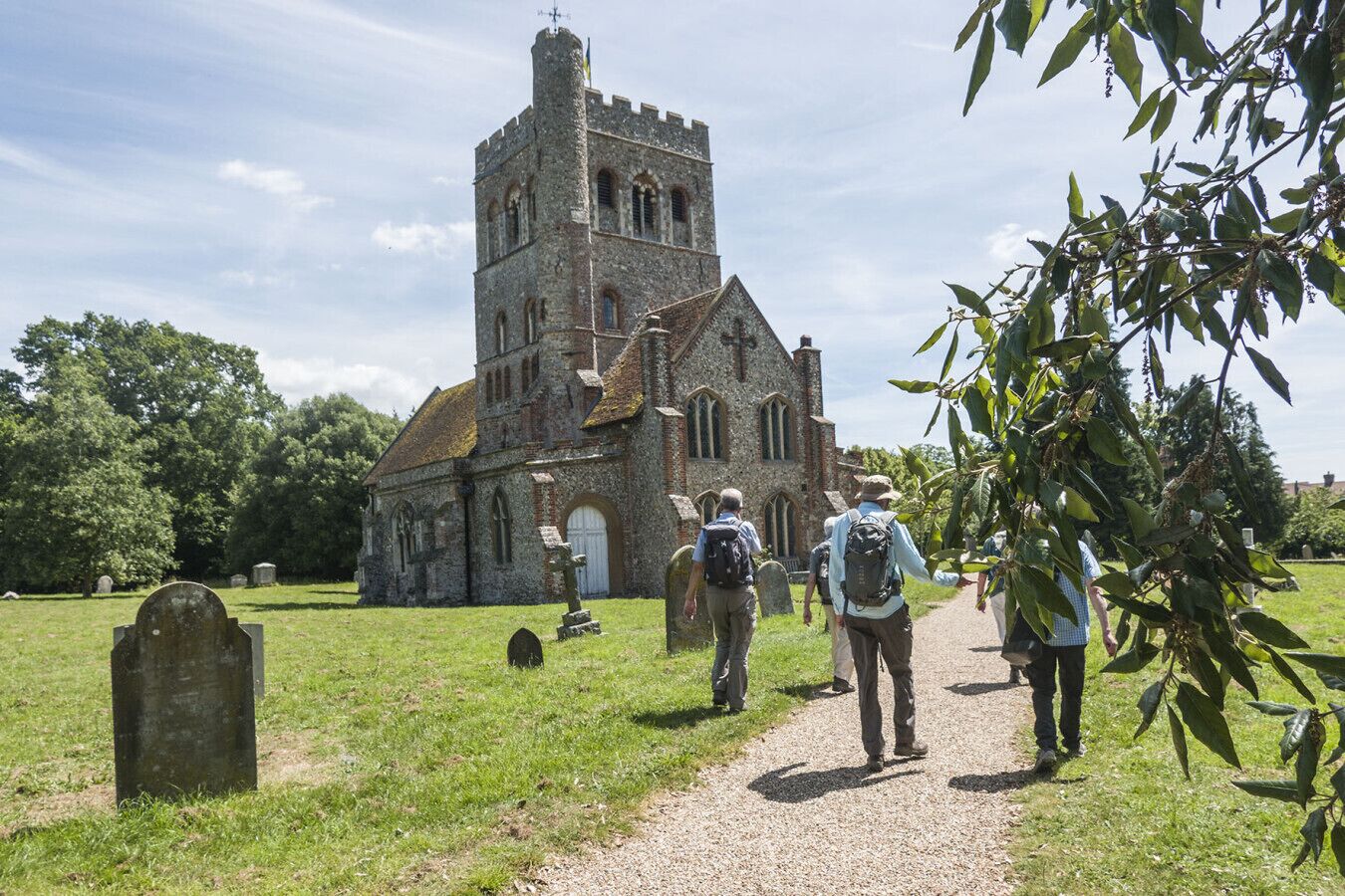 Une église historique dotée d’un haut clocher et d’un chemin de gravier menant à l’entrée.