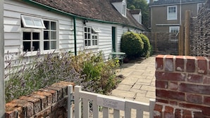 A white cottage with a green door, a brick wall, and a sign that reads "Vicarage Cottage." - Cozy Cottage With Scenic Walks (Great Tey)