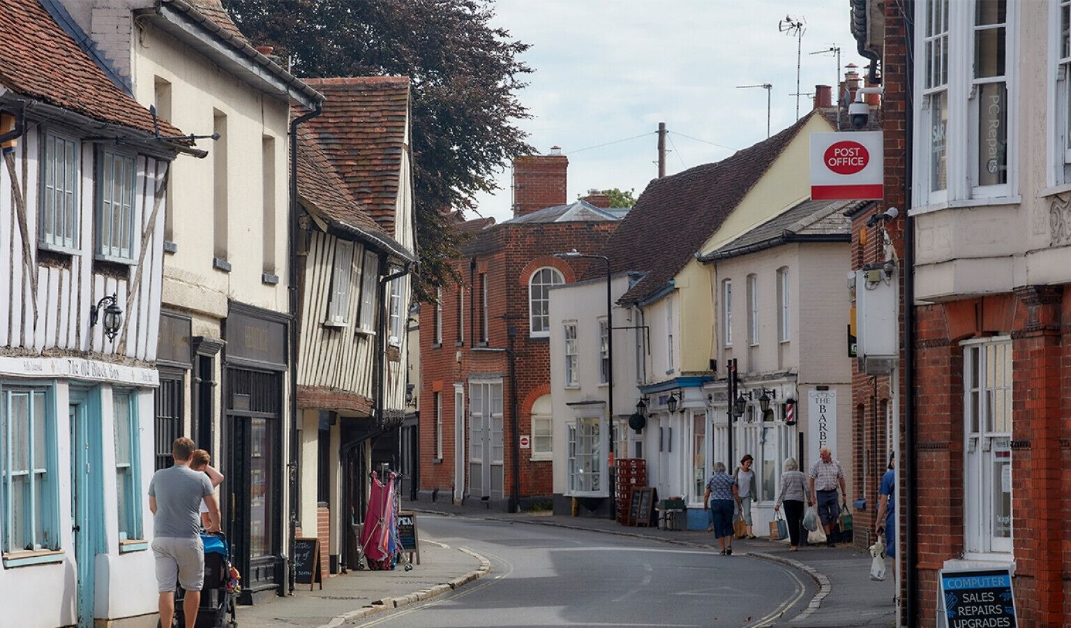 Une rue étroite bordée de bâtiments traditionnels, dont un pub et un bureau de poste.