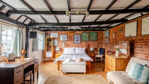 A bedroom with a bed, dresser, desk, and a chair. There are framed pictures on the wall and a window with curtains. - Cozy Cottage With Scenic Walks (Great Tey)