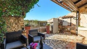 Un patio exterior con mobiliario de mimbre, suelo de piedra y pared de piedra.