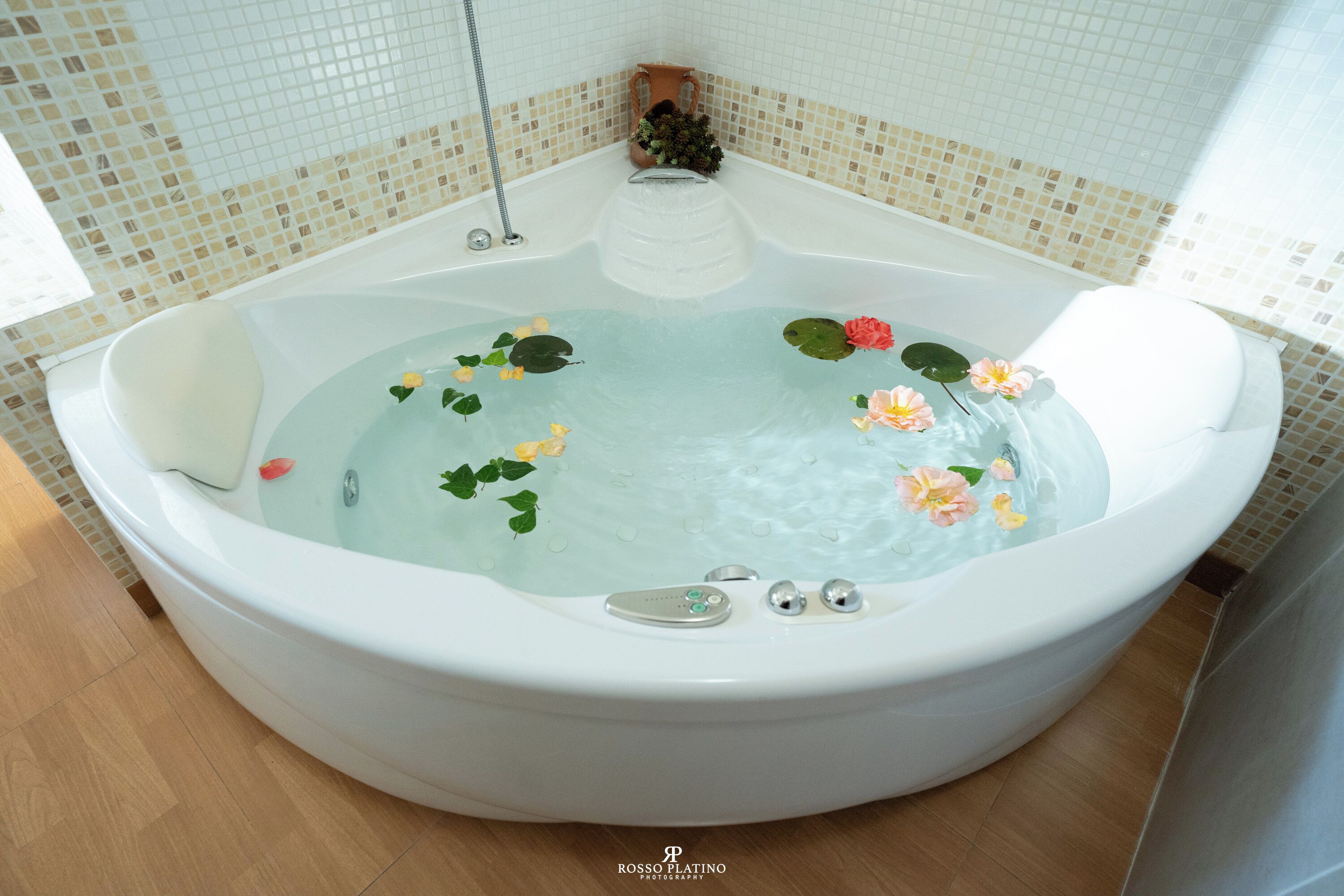 Une grande baignoire ronde et blanche, remplie d’eau, ornée de nénuphars et de fleurs.