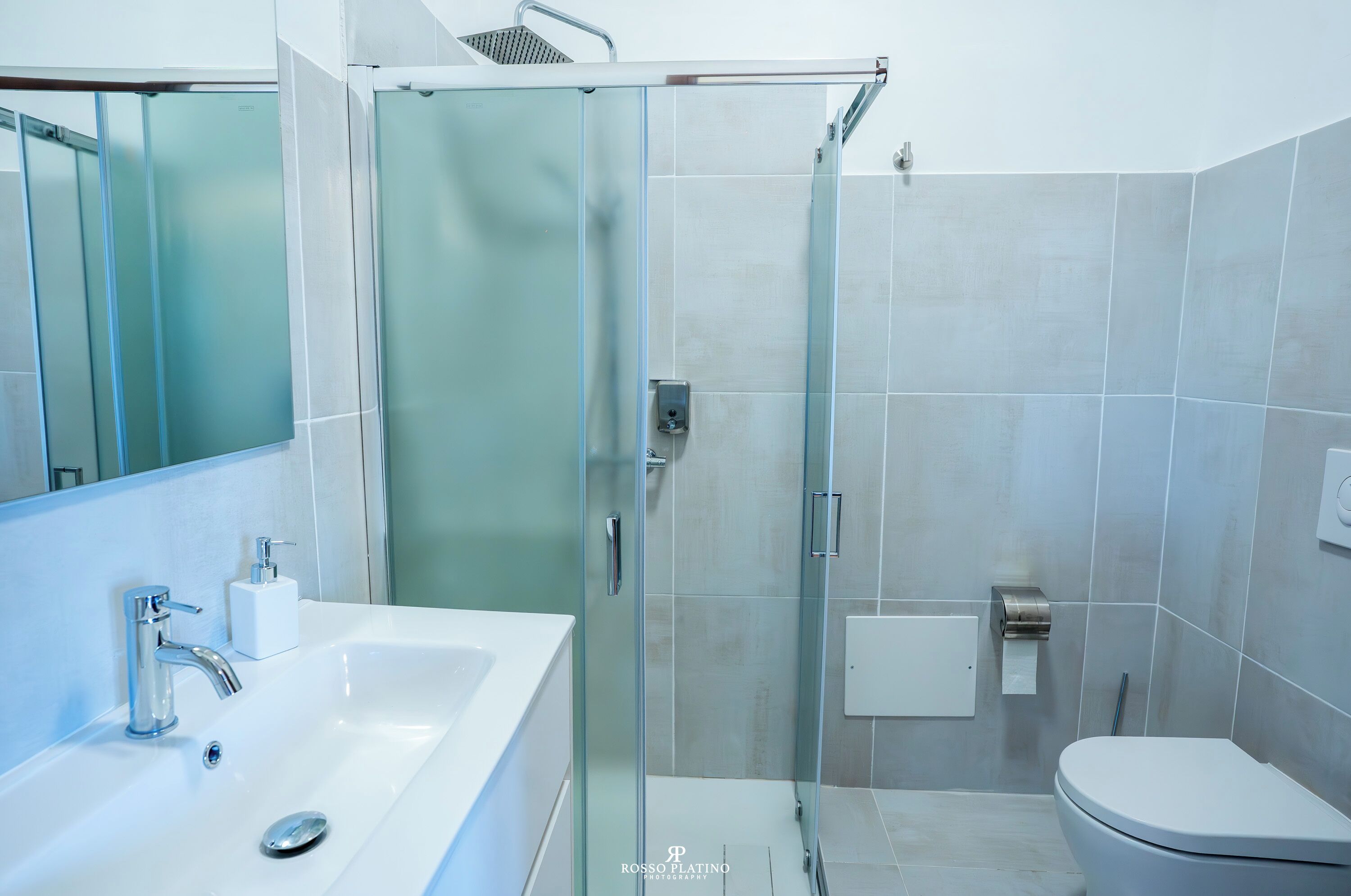 Un bagno moderno con cabina doccia in vetro, lavandino bianco e servizi igienici.