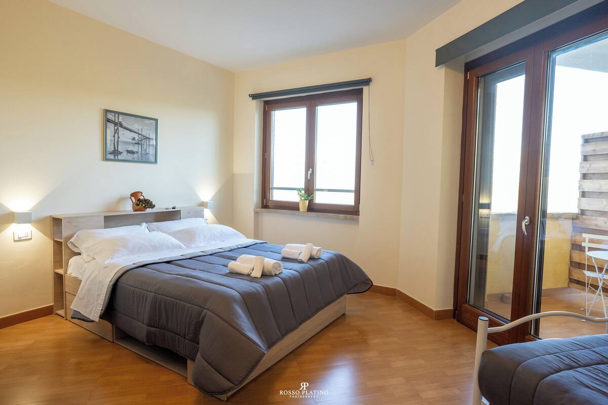 A modern bedroom with a bed, bedside table, and a window with a view.
