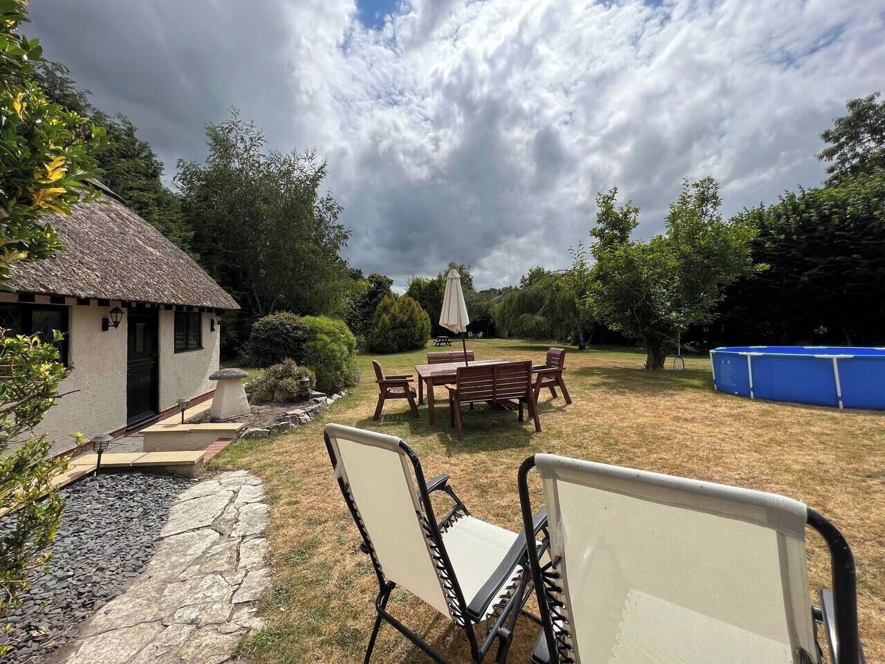 Une terrasse avec une table et des chaises, un petit bâtiment et, au fond, un conteneur bleu.