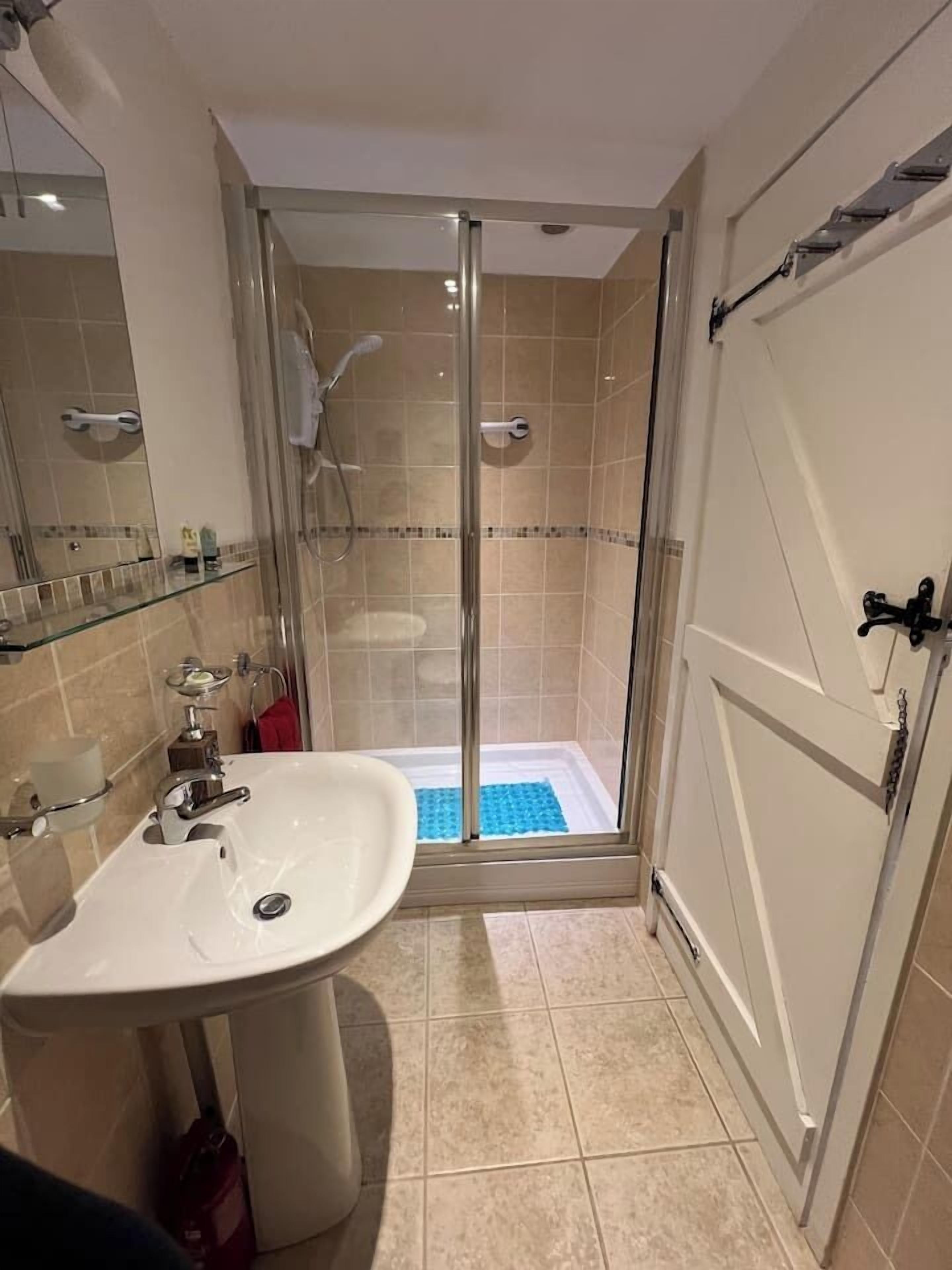 Une salle de bain avec une douche à parois de verre, un lavabo et un miroir.