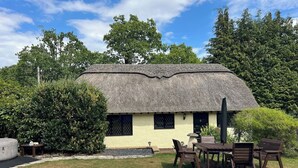A thatched-roof house with a pool and outdoor seating.