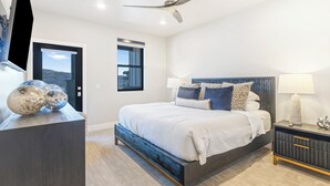 A modern bedroom with a bed, bedside tables, a ceiling fan, and a window with a view.