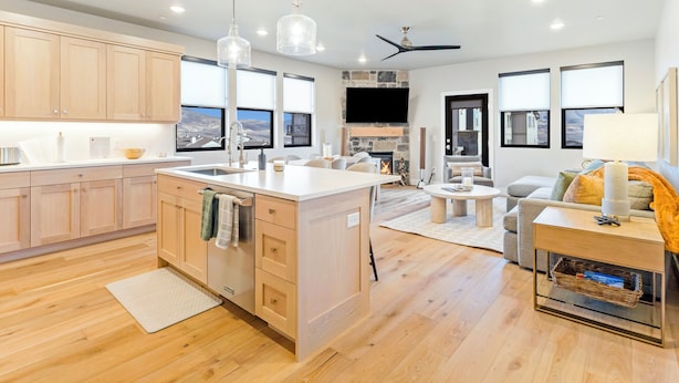 A modern kitchen with wooden cabinets, a central island, pendant lighting, and a fireplace.