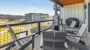 A balcony with outdoor seating, a stone pillar, and a view of a residential area.