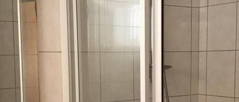 Une salle de bain avec une douche à parois de verre, un lavabo blanc et un miroir.