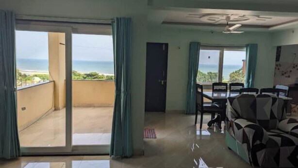 Una habitación con balcón, zona de comedor y sofá.