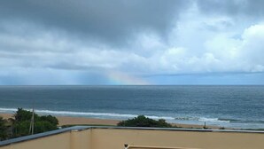 A beach view with a cloudy sky and a rainbow.