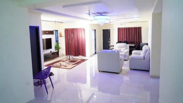 A spacious living area with a flat-screen TV, a sofa, a chair, and a rug.