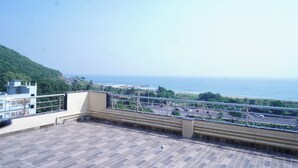 A rooftop terrace with a view of the sea and a highway.