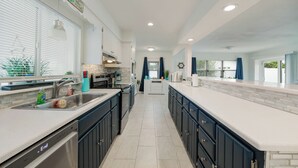 Una cocina moderna con una isla central, electrodomésticos integrados y un ventanal que proporciona luz natural.