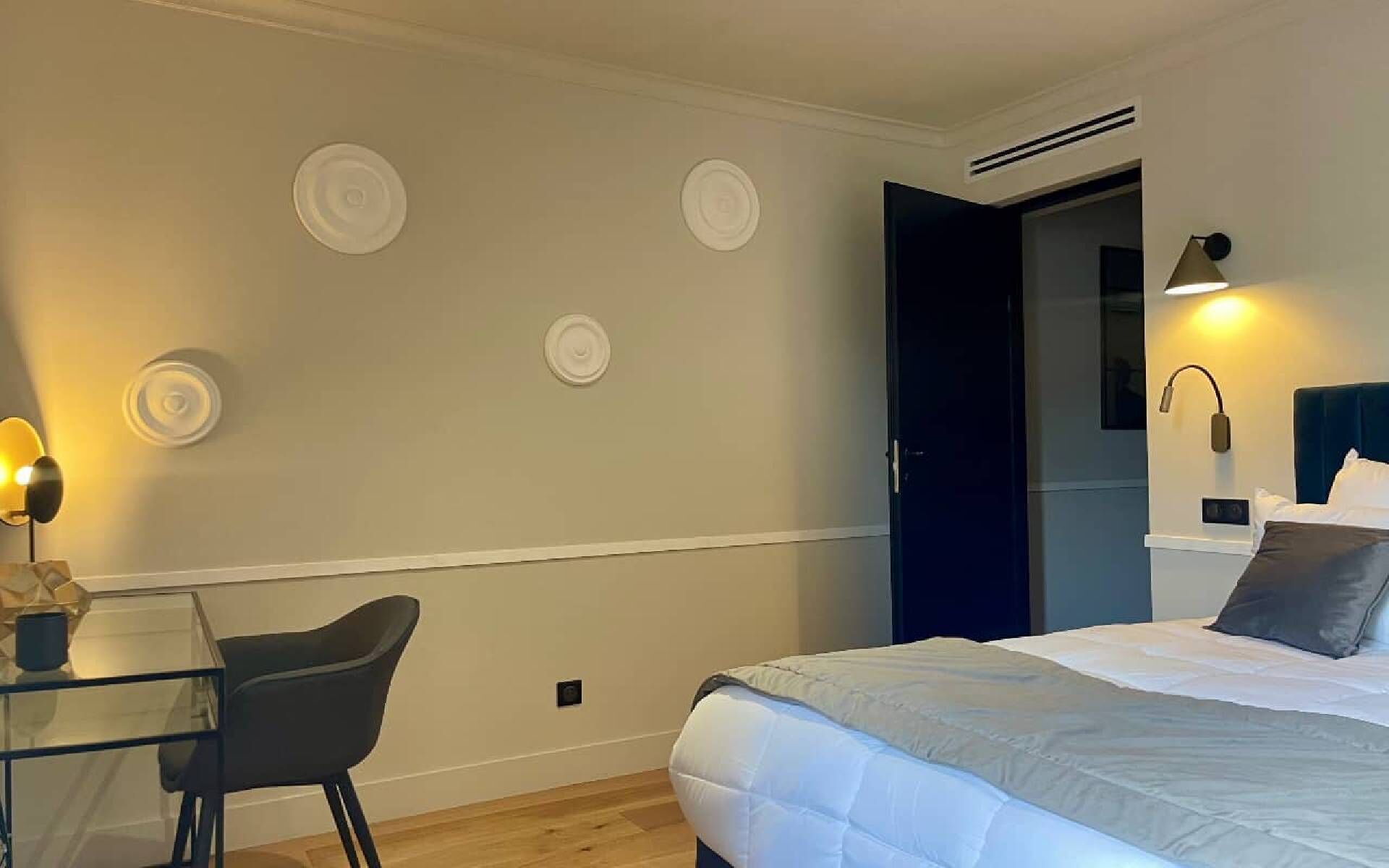 A bedroom with a bed, a desk, a chair, and a door.