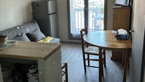 Et kompakt køkken med spiseplads, et køleskab, en mikroovn og et træbord.