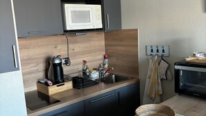 Et moderne køkken med mikroovn, kaffemaskine og vask. Der er en kasse på bordet og en kurv på bordpladen.