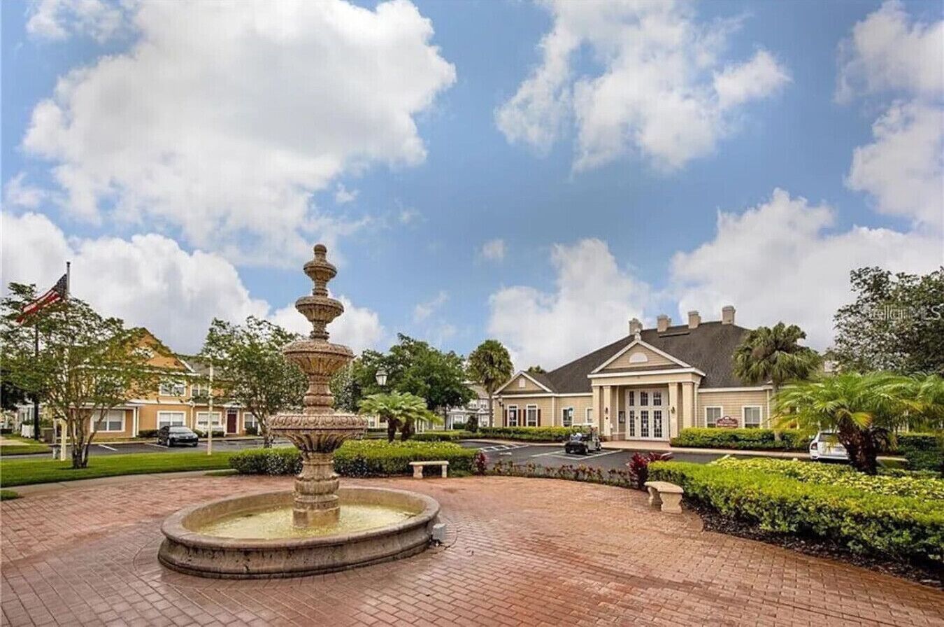 A courtyard with a fountain, a large building with a symmetrical facade, and well-maintained landscaping.