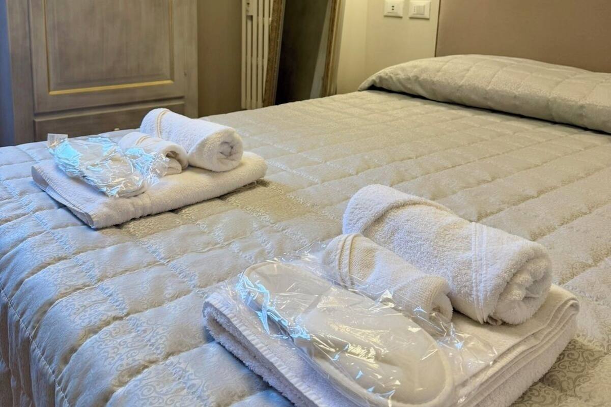 A hotel room with a bed, a wardrobe, a mirror, and a wall-mounted lamp.