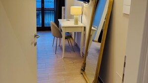 A hotel room with a desk, chair, TV, and a large mirror. - La Boutique by Rjgal  (Florence)