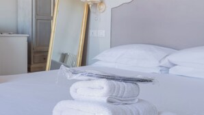A neatly made bed with white linens and towels, a large mirror with a gold frame, and a painting on the wall. - La Boutique by Rjgal  (Florence)