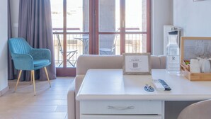 A hotel room with a white desk, a blue chair, a chandelier, a balcony with a view, and a framed picture on the wall. - La Boutique by Rjgal  (Florence)
