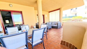 Un'area pranzo all'aperto coperta, con tavolo e sedie, un divano e un barbecue.