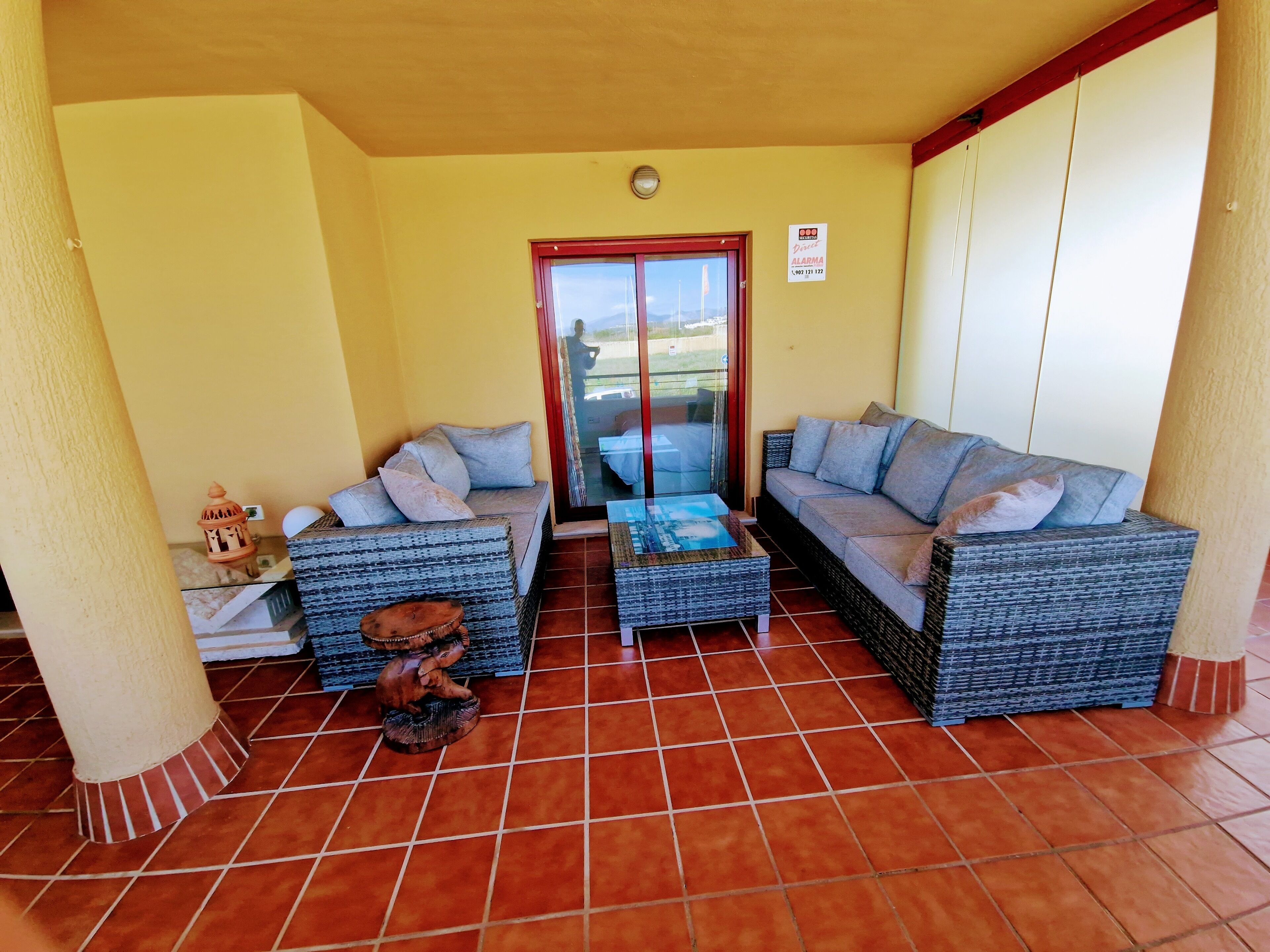 A furnished patio area with two sofas and a coffee table, a small decorative item, and a tiled floor.