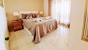 Camera d'albergo con un letto, un comodino, una lampada e una ventola a soffitto.