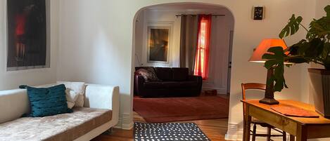 A living room with a sofa, a coffee table, a rug, and a dining table with chairs.