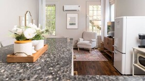 Una cocina moderna con encimera de granito, un refrigerador, una silla y una mesa de comedor con un florero.