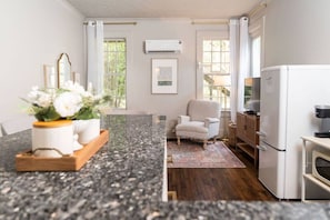 A modern kitchen with a granite countertop, a refrigerator, a chair, and a dining table with a vase of flowers.