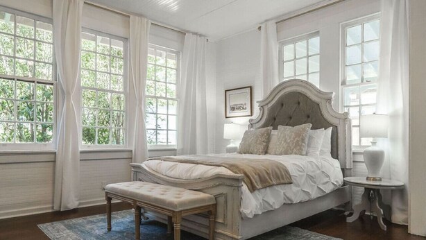 A bedroom with a large bed, a bench, and a nightstand. - Historic Park Place Retreat  3 Bdrm on the Park (Columbus)