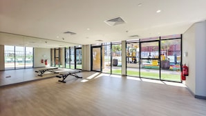A spacious gym with large windows, exercise equipment, and a fire extinguisher. - Relaxing Studio Retreat in Vibrant Meydan City, (Dubai)