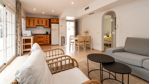 A spacious living area with a sofa, a dining table with chairs, and a kitchen in the background. - Charming Coastal Home (Marbella)