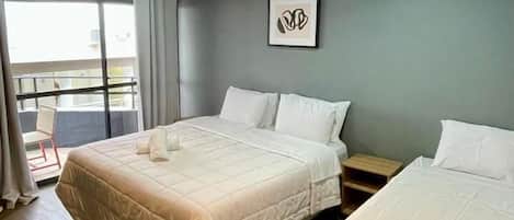Habitación de hotel con dos camas, balcón y lámpara en el techo.