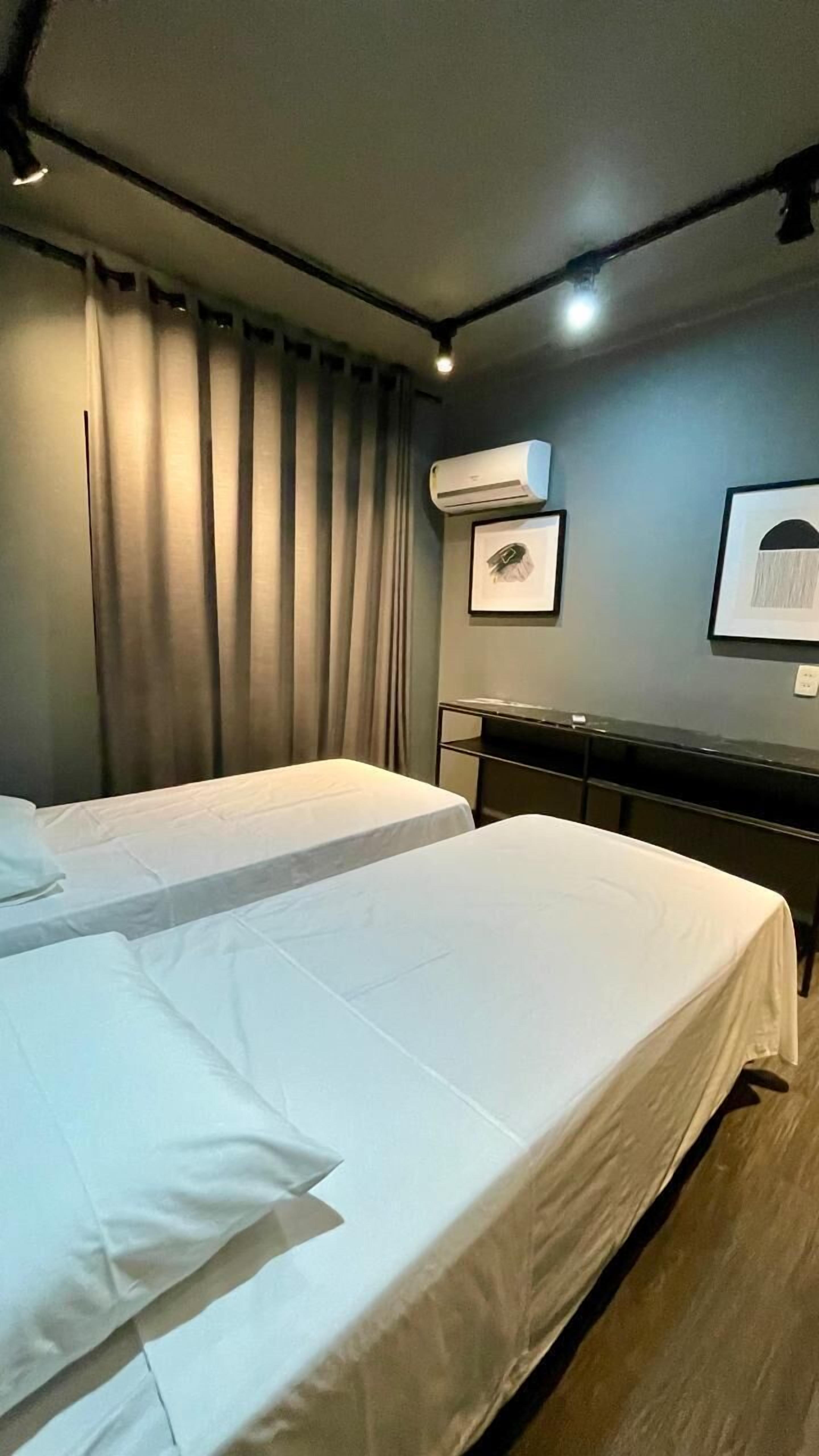 Une chambre d’hôtel avec deux lits, un ventilateur de plafond, un appareil de climatisation et un tableau encadré au mur.